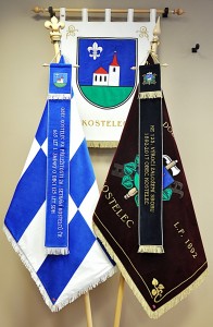 Vyšívané symboly obce Kostelce - znak, obecní vlajka, hasičský prapor a pamětní stuhy.