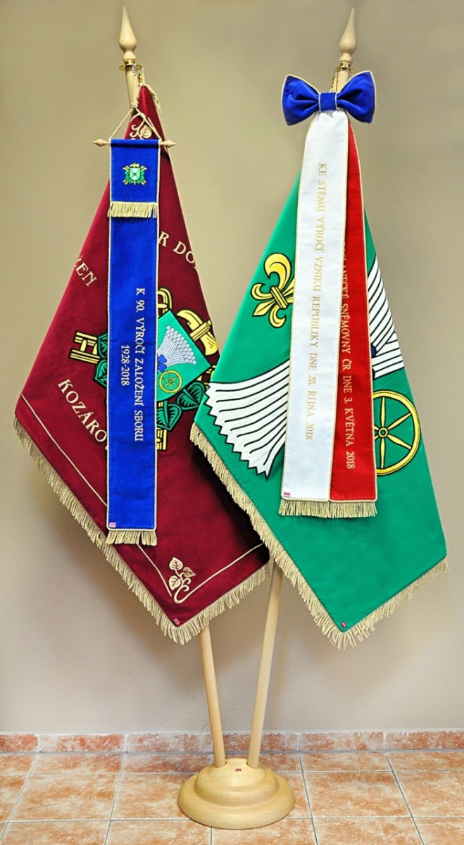Vyšívané symboly pro obec a SDH Kozárov vyvěšené na dvoudílných  žerdí.