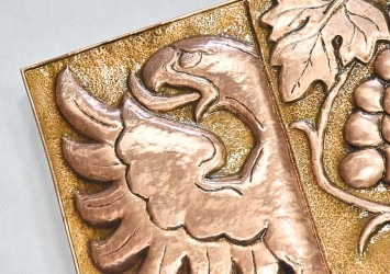 Detail měděného městského znaku s lesklým zalakováním.
